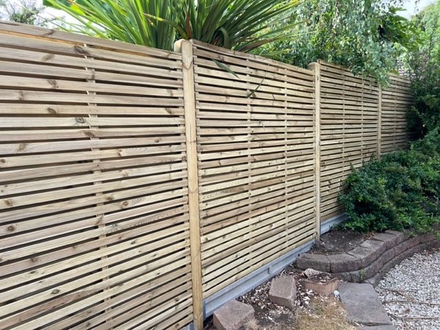 Horizontal slatted timber fencing installed around a modern residential garden
